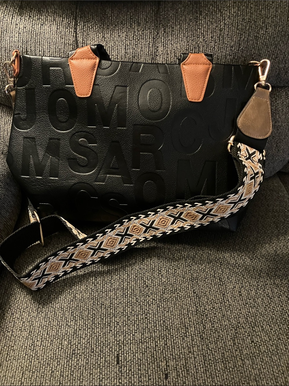 Black Embossed Messenger Bag with Tan Accent Tabs and Patterned Strap